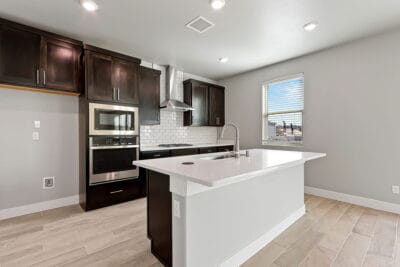 Modern kitchen with spacious island and large window in Zen floorplan home, showcasing open living space.